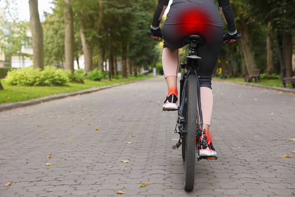 Problem of injured coccyx. Woman riding bicycle on road - Valokuva, kuva