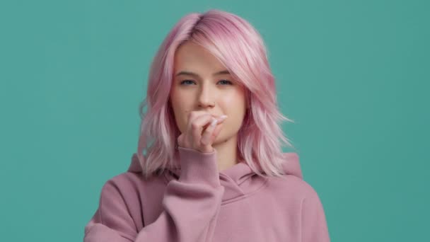 Slow motion studio shot roze harige jonge vrouw van 20 in roze hoodie recht in de camera kijken en tonen ritsen, sluiten mond gebaar visualiseren stilte, stoppen wil niet praten in slow motion - Video