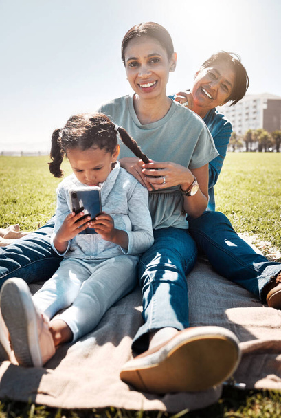 Family, picnic and park with child, mother and grandma sitting together on grass to relax, bond and smile with three generation girls having fun. Portrait of woman, girl kid and senior lady in nature. - Foto, imagen