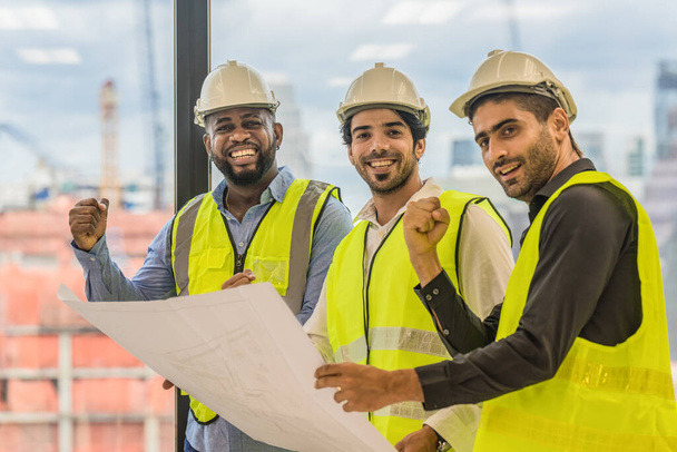 engineering industry and business background of three civil engineer standing together raise fist up to show teamwork and confident for project success - Photo, Image