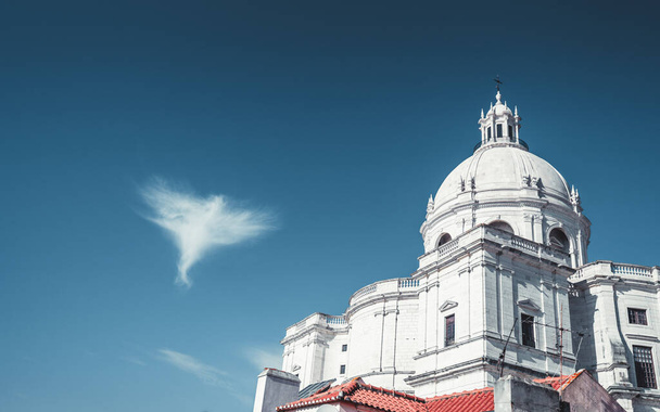 View of The Church of Santa Engracia or another name National Pantheon on a very sunny day, with a blue sky and a single cloud in the shape of an angel next to the dome and walls of the church - 写真・画像
