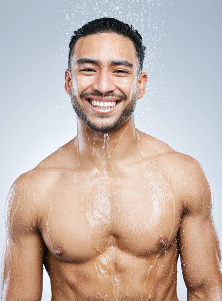 I always feel tons better after a shower. Studio portrait of a handsome young man taking a shower against a grey background - Foto, afbeelding