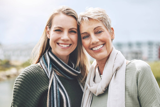 Happy, mother and daughter with smile in nature together in the city of Australia. Face portrait of a young woman with a senior person in the city or park together with love and to relax in happiness. - Fotó, kép