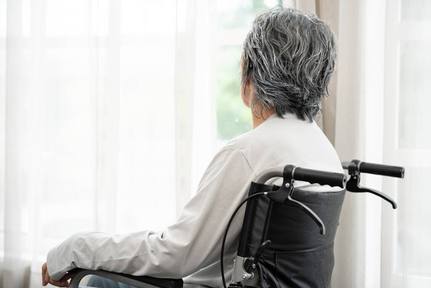 Female senior sit in wheelchair look in distance feel lonely, thoughtful sad handicapped mature woman in wheel chair thinking. Person with a disability. suffering from loneliness, thinking of future. - Photo, Image