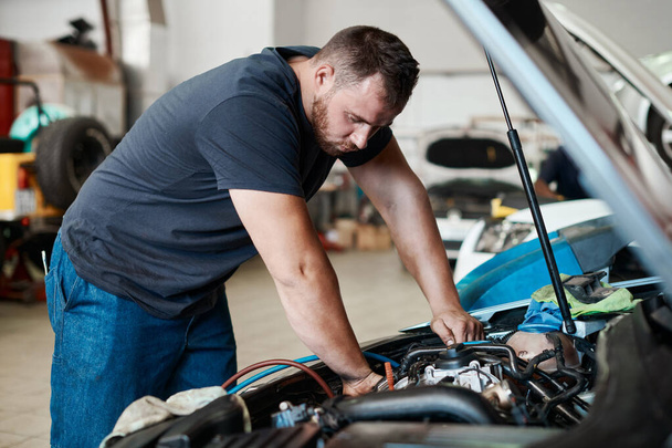 Donner à votre moteur les soins dont il a besoin. un mécanicien travaillant sur une voiture dans un atelier de réparation automobile - Photo, image