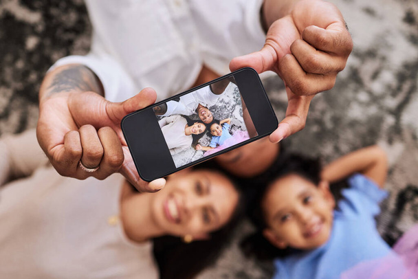 Famiglia, mani e telefono per selfie foto rilassante sul pavimento con sorriso per divertimento, legame e momenti insieme. Mano di felice padre, madre e bambino sorridente per l'immagine immagine perfetta su smartphone. - Foto, immagini