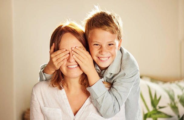 Close your eyes. an adorable little boy bonding with his mother at home and covering her eyes to surprise her - Foto, afbeelding