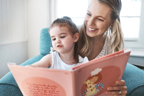 Book, family and love with a mother and daughter reading a story on a couch in the living room of their home together. Children, love and education with a woman and daughter bonding over a storybook. - Foto, imagen