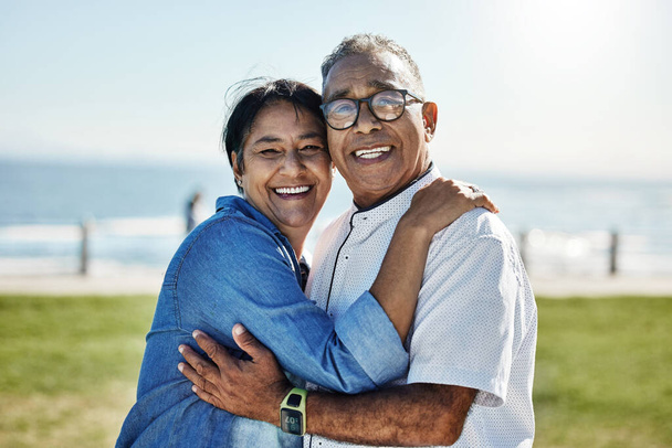 Love, hug and happy senior couple enjoy romantic quality time together, travel vacation or bond on outdoor grass field. Happiness, partnership and elderly man, woman or people smile on Mexico holiday. - Photo, Image