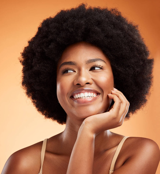 Beauty, black woman and happy wellness, aesthetic or natural makeup, glowing skincare and clean cosmetics on orange studio background. Smile young female model face, afro hair or thinking inspiration. - 写真・画像