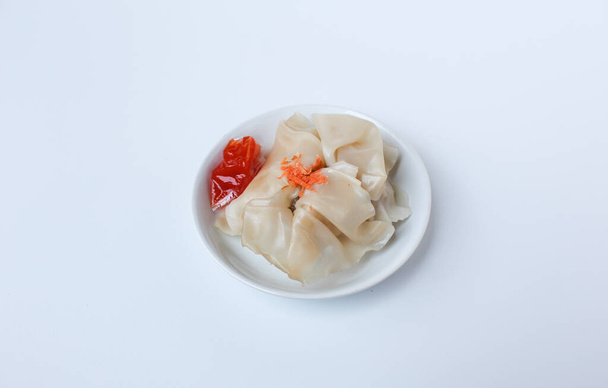 Προσιτή έκδοση των dumplings, με ένα μικρό πακέτο σάλτσα. Απομονωμένα σε λευκό φόντο - Φωτογραφία, εικόνα