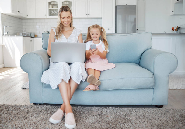 Család, telefon és laptop egy lánnyal és anyával a kanapén egy otthoni nappaliban együtt munka közben vagy a közösségi médiában. Számítógép, e-mail és kommunikáció egy nő és lánya egy házban. - Fotó, kép