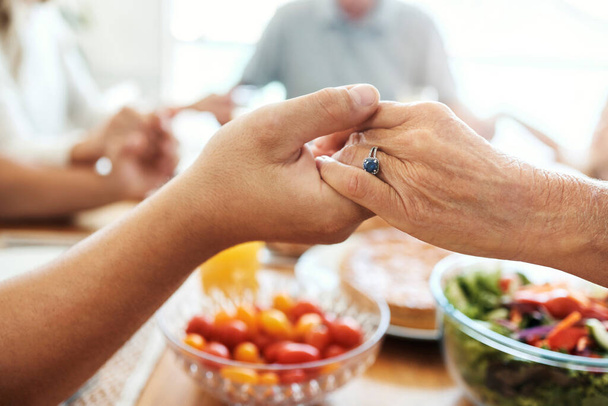 Praying, holding hands and food of family at dining room table with faith, gratitude and christian lifestyle. Prayer together, trust and spiritual people with healthy lunch, brunch or holiday meal. - Фото, зображення