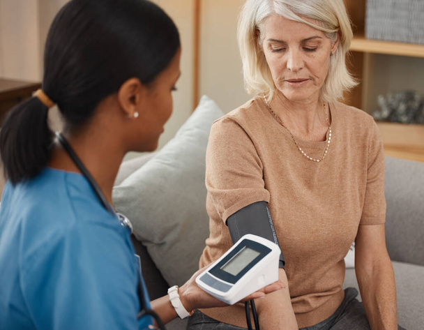 Bueno, necesito monitorear su presión durante unos meses. un médico examinando a una mujer mayor con un indicador de presión arterial en casa - Foto, Imagen