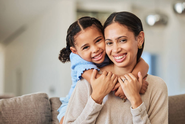 Love, relax and mother and girl on sofa with hug for family, happy and lifestyle together. Smile, support and trust with portrait of mom and child in living room at home for care, youth and happiness. - Photo, image