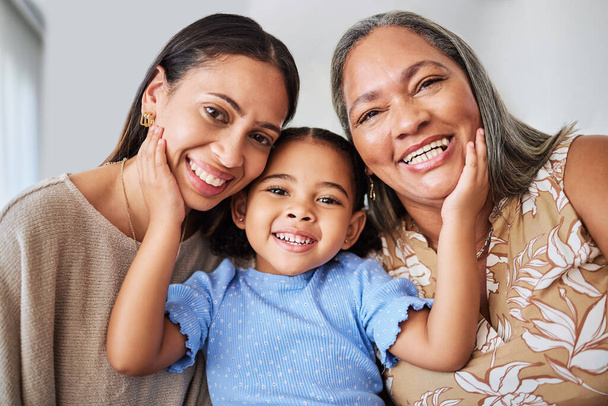 Mother, girl and grandma bond in living room, smile, relax and hug in their home. Face, portrait and happy family of multigenerational women hug, laugh and enjoying quality time at home together. - Photo, Image