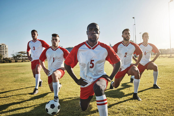Футбол, чоловіки та команда розтягуються на полі перед спортивною грою або тренувальними вправами. Здоров'я, фітнес і командна робота, гравці футбольних змагань тягнуться на траві разом для сильної продуктивності в матчі
 - Фото, зображення