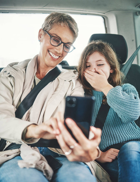 Phone, surprise and mother with child on car journey, travel or road trip for adventure, bond or fun quality time together. Love, shock or transport for kid girl with happy mom streaming online movie. - 写真・画像