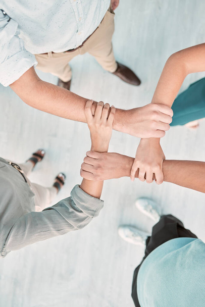 Hände, Zusammenarbeit und Einheit mit einem Geschäftsteam, das die Arme in einem Büro von oben zusammenhält. Vertrauen, Unterstützung und Teamarbeit mit einer Gruppe von Männern und Frauen, die in Solidarität oder Glauben stehen. - Foto, Bild