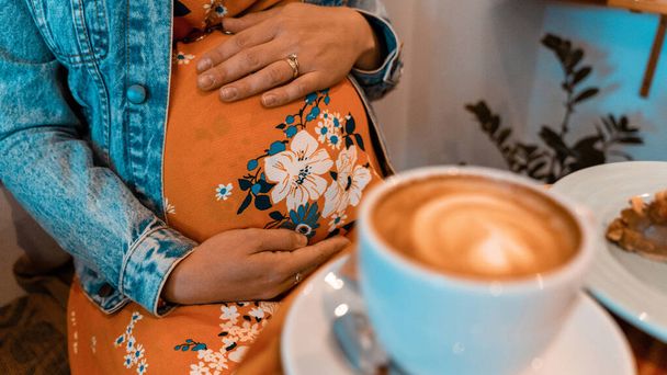 Woman coffee cup pregnancy drink. Happy pregnant girl drink hot coffee in restaurant. Represent breakfast, energy, freshness or great aroma concept - Photo, image