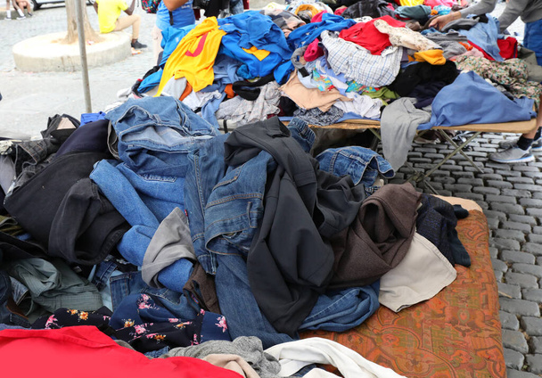 stapel gebruikte kleding op de rommelmarkt op het dorpsplein - Foto, afbeelding