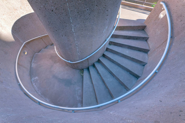 San Antonio, Texas- Vista superior de una escalera de caracol de hormigón. Vista de ángulo alto de una escalera de caracol con pasamanos montados en la pared y pared de hormigón y escalones. - Foto, Imagen