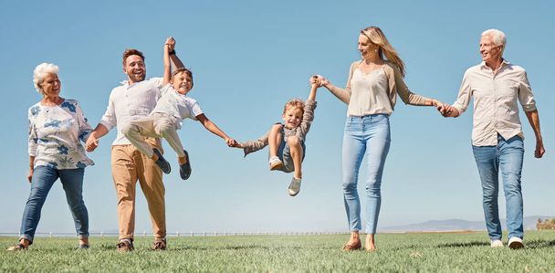 Winda, szczęśliwa rodzina i letni spacer na polu, zabawy i zabawy w przyrodzie razem, uśmiech i śmiech. Rodzice, dzieci i dziadkowie uwielbiają rozmawiać lub spędzać czas z rodziną, uśmiechać się i trzymać za ręce na świeżym powietrzu. - Zdjęcie, obraz