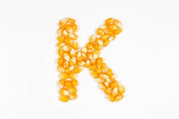 Brief K van het Engelse alfabet van droge popcorn zaden op witte achtergrond. - Foto, afbeelding