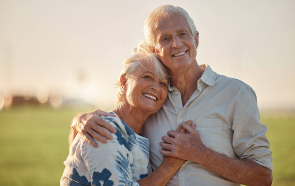 Senioren paar glimlachen en blij met liefde buiten in een bos, zorg en knuffel. Oudere man en vrouw portret, geluk en rustige dag in de natuur, genieten van pensioen en gezonde relatie op het veld. - Foto, afbeelding