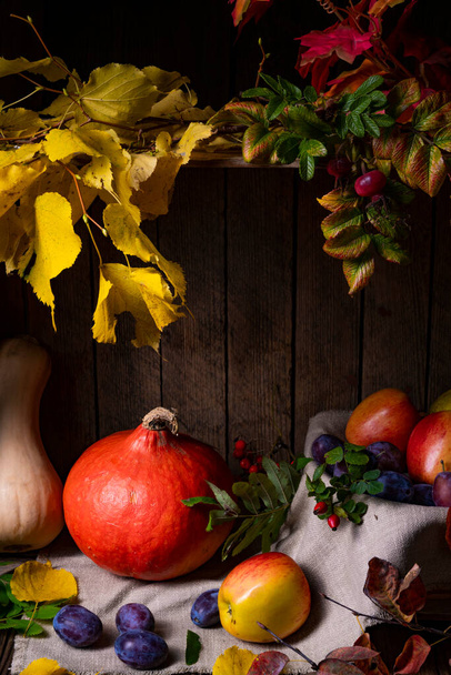 Various fruits in a wooden box with autumn leaves - Foto, afbeelding