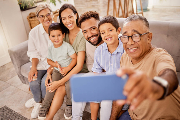 Selfie, family and phone with grandfather taking a photograph of his grandchildren and their parents at home. Kids, photo and big family smile, happy and social media in living room with smartphone. - Foto, Bild