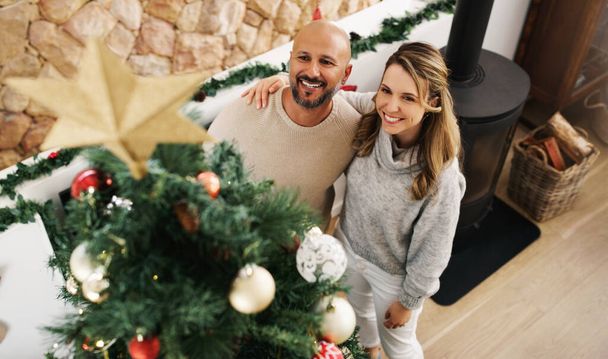 The best Christmas gift is appreciating everything you already have. a happy couple decorating their Christmas tree at home - Zdjęcie, obraz