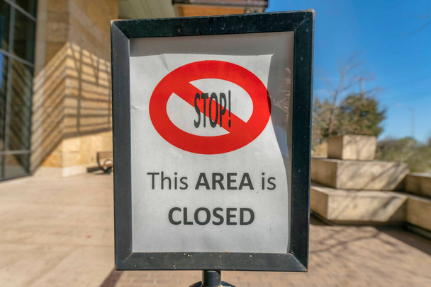 Austin, Texas- Gerahmte Beschilderung mit Stop This Area ist geschlossen. Nahaufnahme eines Hinweisschildes mit einem verschwommenen Hintergrund aus Gebäude und Himmel im Hintergrund. - Foto, Bild