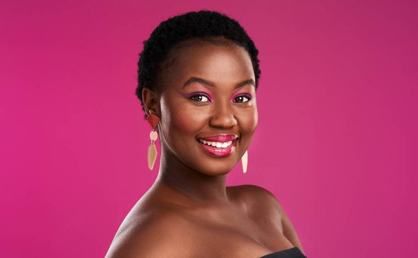 It doesnt cost a penny to smile. Studio shot of a beautiful young woman posing against a pink background - Foto, immagini