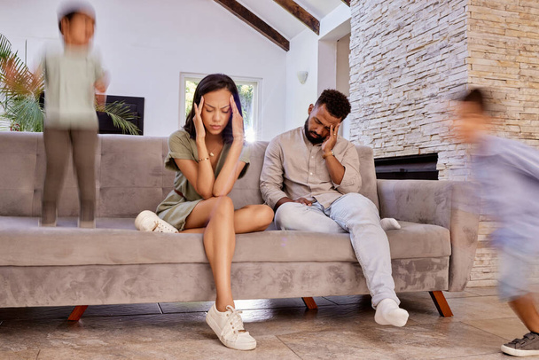 Kids, stress and headache with a black couple in the living room of a house while crazy adhd children run around. Family, anxiety and depression with a mother, father and busy boy siblings at home. - Photo, Image