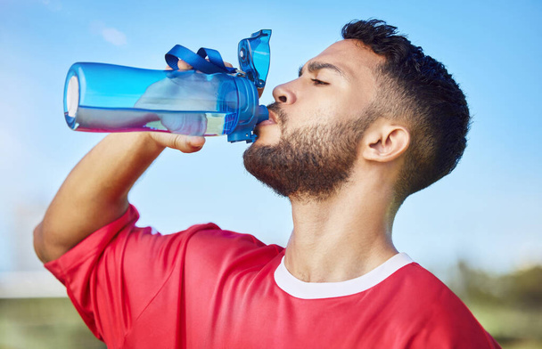 Man, soccer and hydration drinking water for sports, health and energy in fitness outdoors. Athletic football player with drink for refreshing, thirsty and sustainability sport training or exercise. - Photo, Image