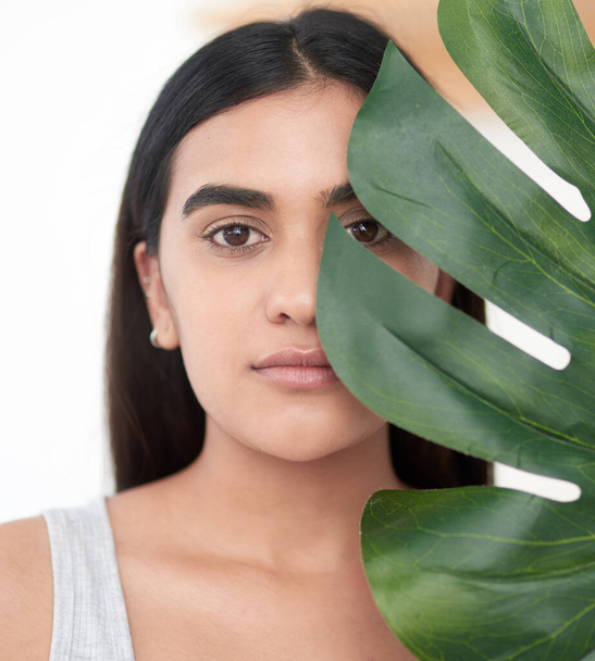 Usa la naturaleza para nutrir tu piel. una hermosa joven sosteniendo una fronda de palma contra su cara - Foto, imagen