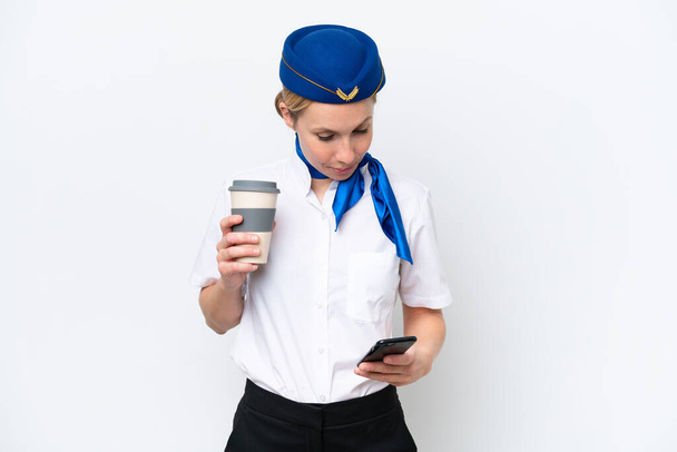 飛行機ブロンドスチュワーデス女性隔離オンホワイト背景保持コーヒーに取り去るとモバイル - 写真・画像