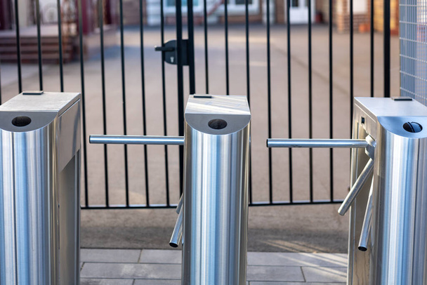 row of gray iron turnstiles on the sidewalk. Photo of turnstiles on a modern city deserted street in spring sunny weather. checkpoint - Photo, Image