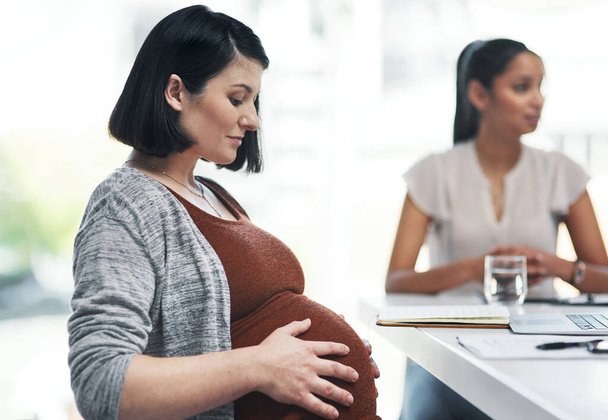 La gravidanza la distrae dal loro progetto. una giovane donna incinta che ha una riunione di squadra in un ufficio moderno - Foto, immagini