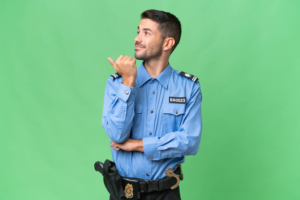 Young police caucasian man over isolated background pointing to the side to present a product - Photo, Image