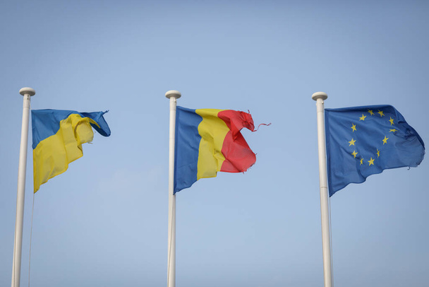 Worn out Ukrainian, Romanian and European Union flags at a border crossing between Ukraine and Romania. - Photo, Image