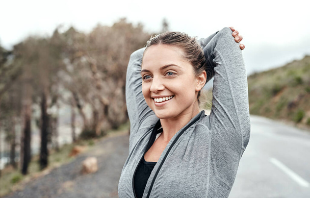 Увеличение подвижности суставов и мышц. Спортивная молодая женщина, растягивающая руки во время занятий на открытом воздухе - Фото, изображение