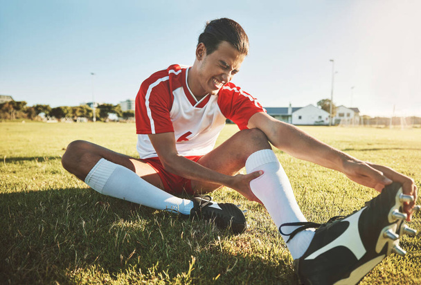Soccer, athlete and injury on sport field while exercise, workout and practice suffer on game day. Football, health and painful leg from training, sore or muscle for stretching, fallen or foot pain. - Foto, Imagem