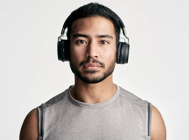 Voin ja teen sen - katso minua. Studio muotokuva urheilullinen nuori mies yllään kuulokkeet valkoista taustaa vasten - Valokuva, kuva