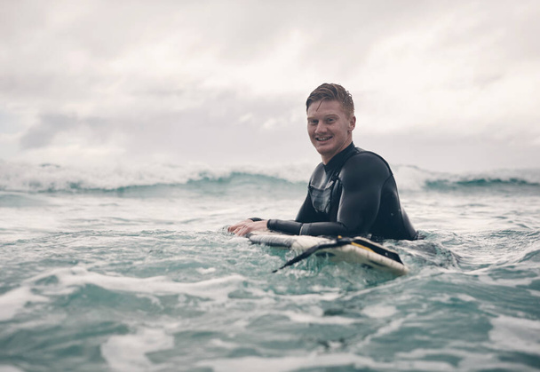 Ik zou in het water leven als ik kon. een jonge man die aan het surfen is op het strand - Foto, afbeelding