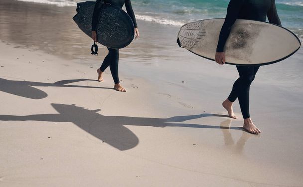 The waves are calling. two people carrying surfboards while walking on the beach - Φωτογραφία, εικόνα