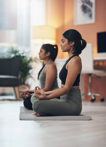 Boa energia é contagiosa. duas jovens mulheres meditando em casa - Foto, Imagem