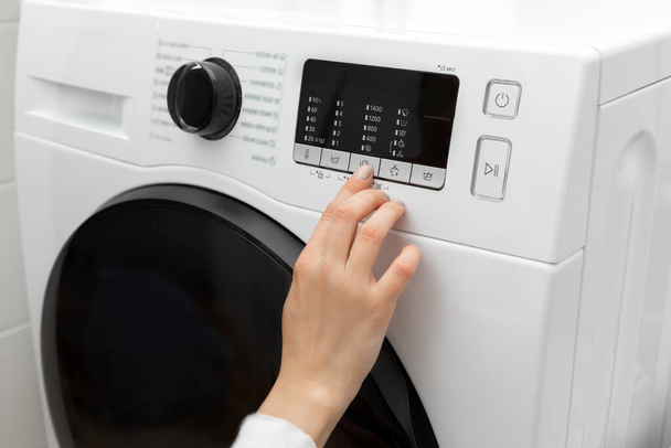 Primer plano de una mano seleccionando un programa con un dedo mientras presiona una lavadora. Foto de alta calidad - Foto, imagen