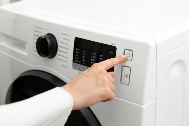 Крупним планом жіноча рука, яка натискає і вимикає пральну машинку. Високоякісна фотографія
 - Фото, зображення